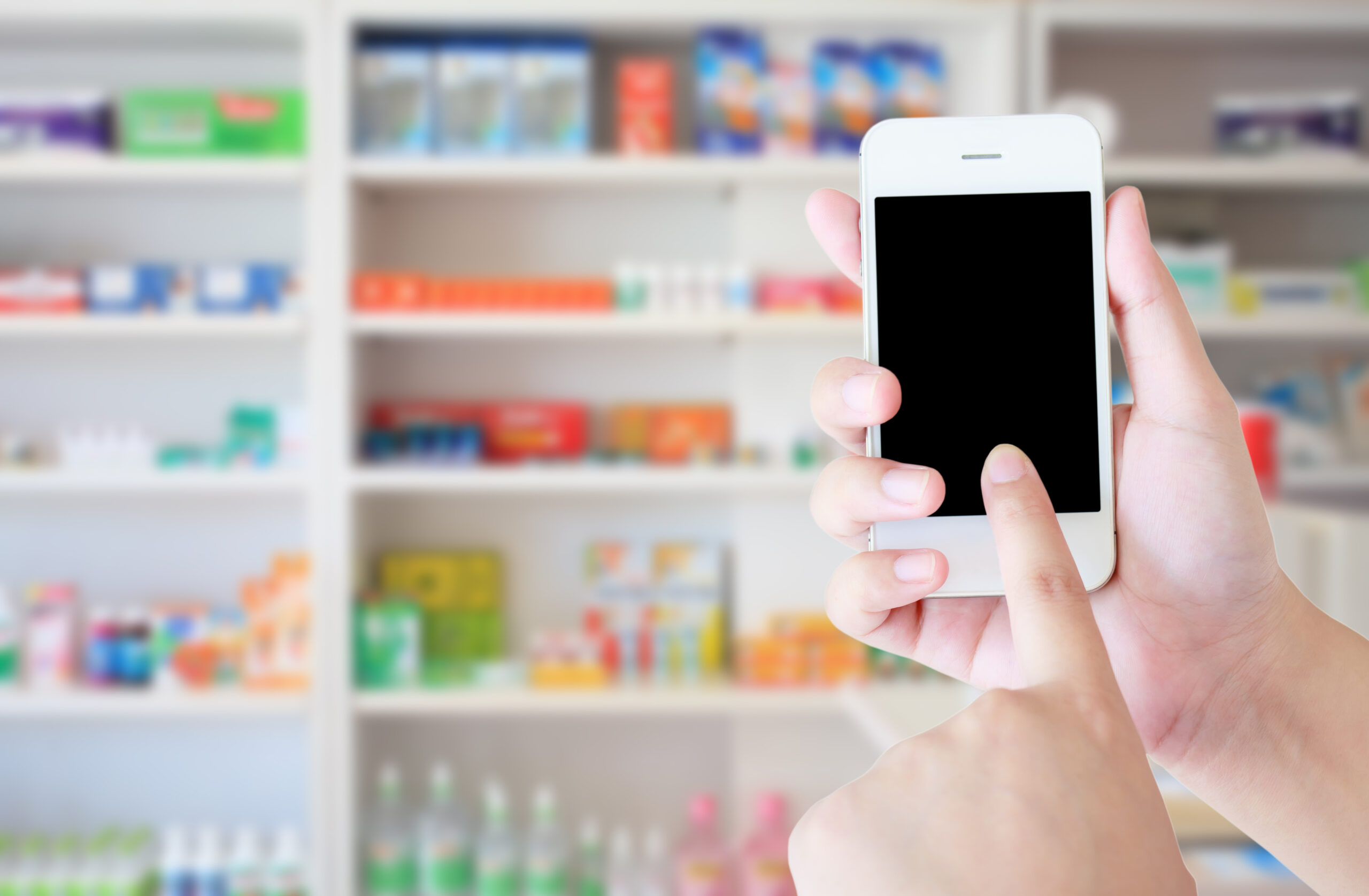 pharmacist hand holding smart phone with blur some shelves of drug in the pharmacy drugstore